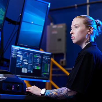 Bucket Image. Tattooed young woman at computer workstation