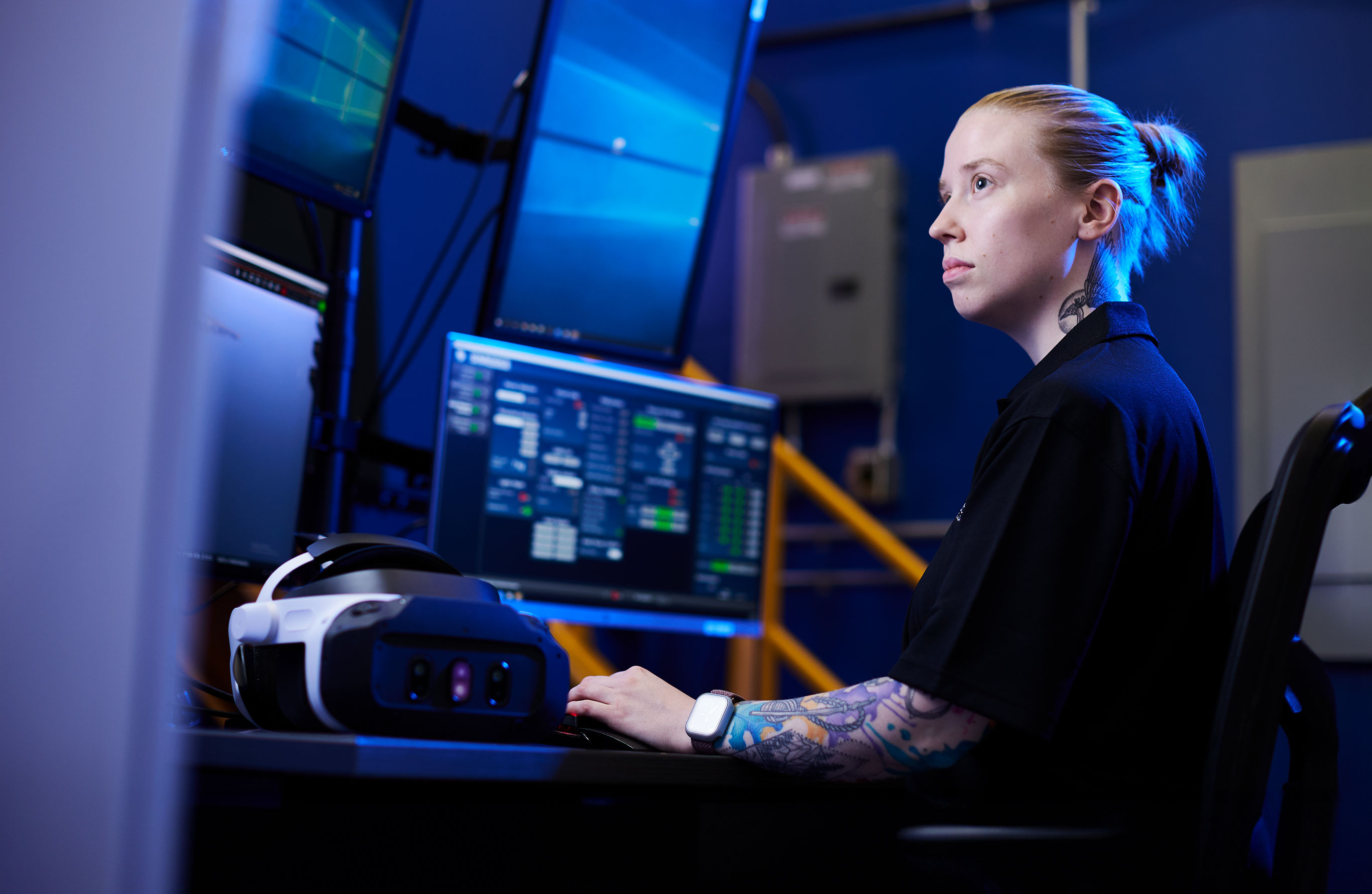 Header Image. Tattooed young woman at computer workstation